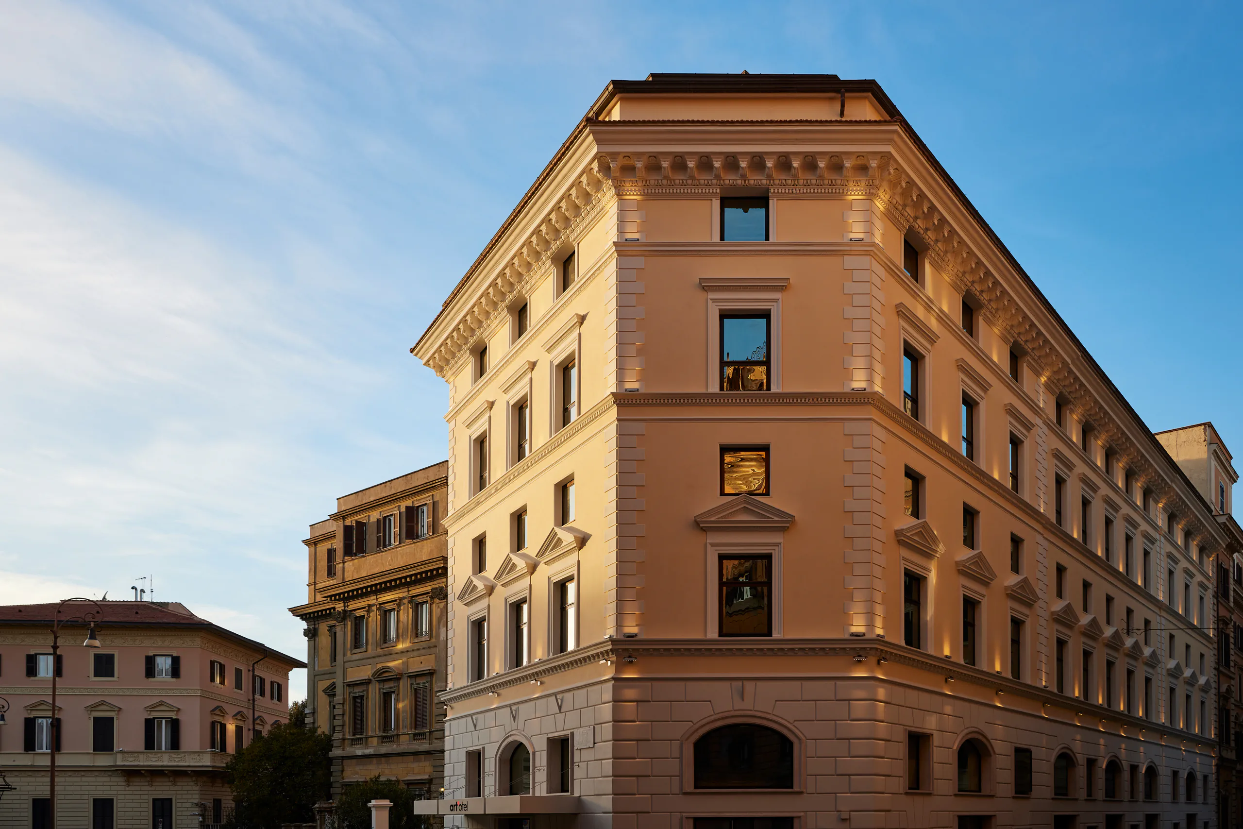 Exterior of an elegant historic corner building against a blue sky — art'otel, Rome