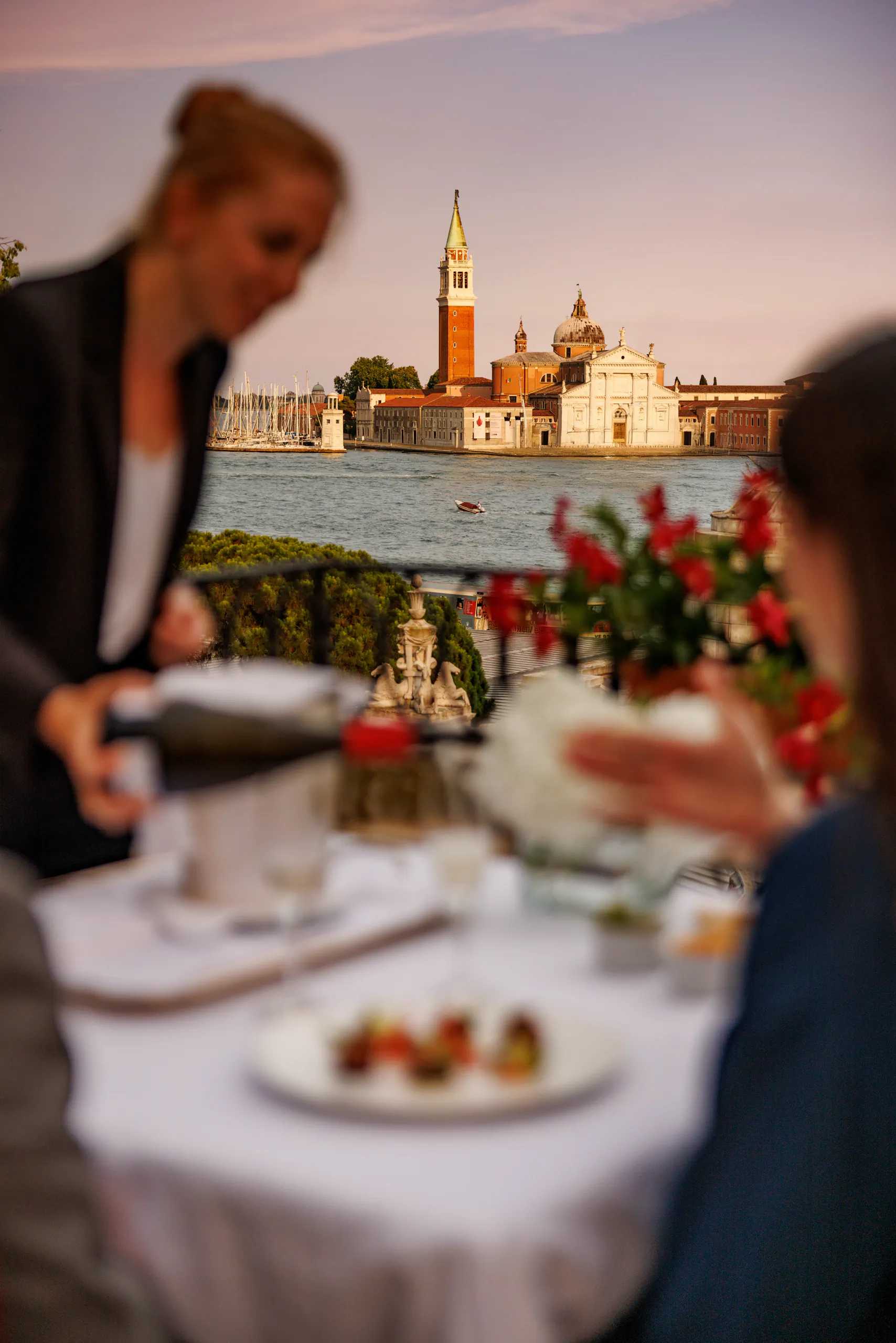 Terrace restaurant table by the Venice lagoon with a waiter serving