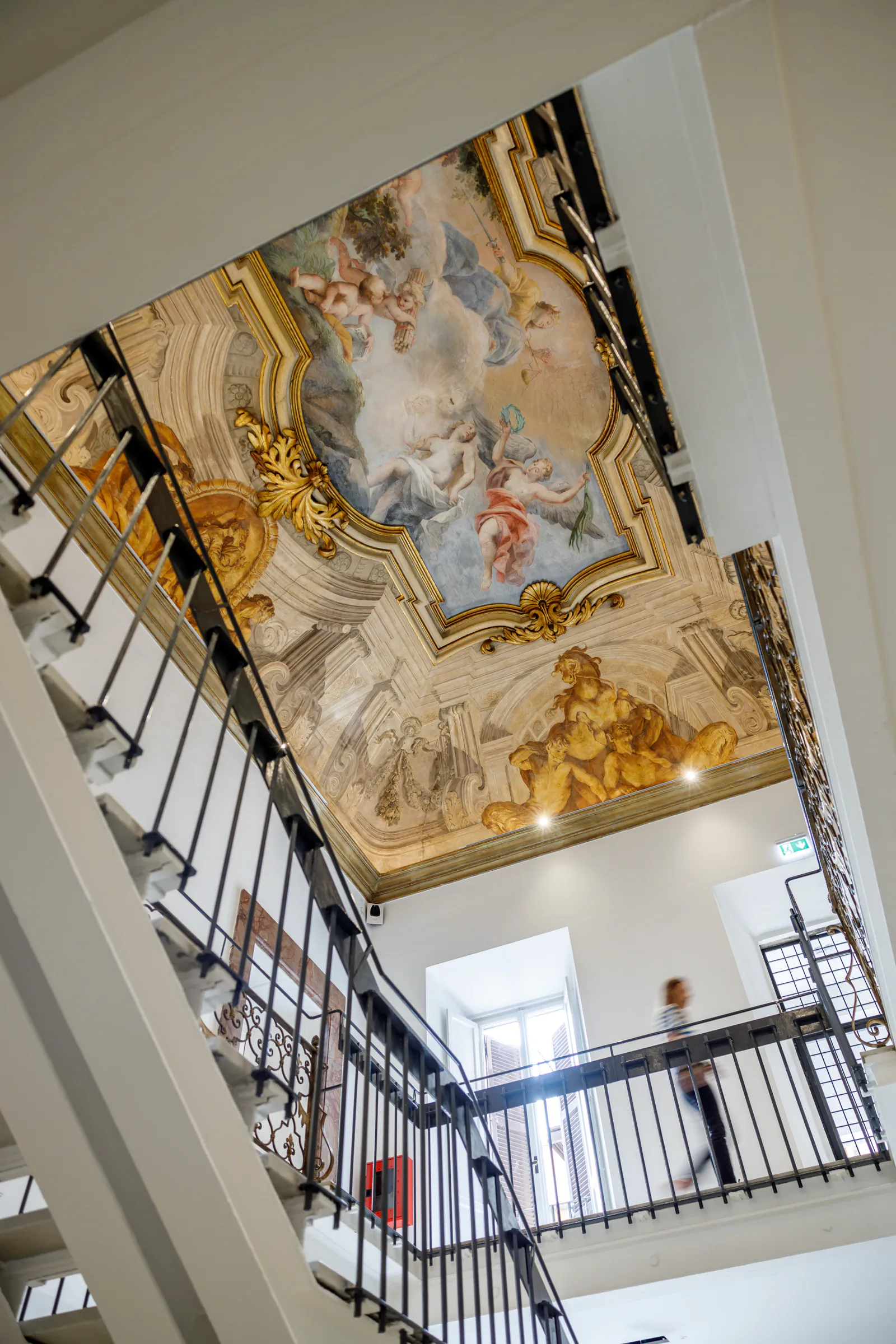 Grand frescoed ceiling above a staircase in a historic building
