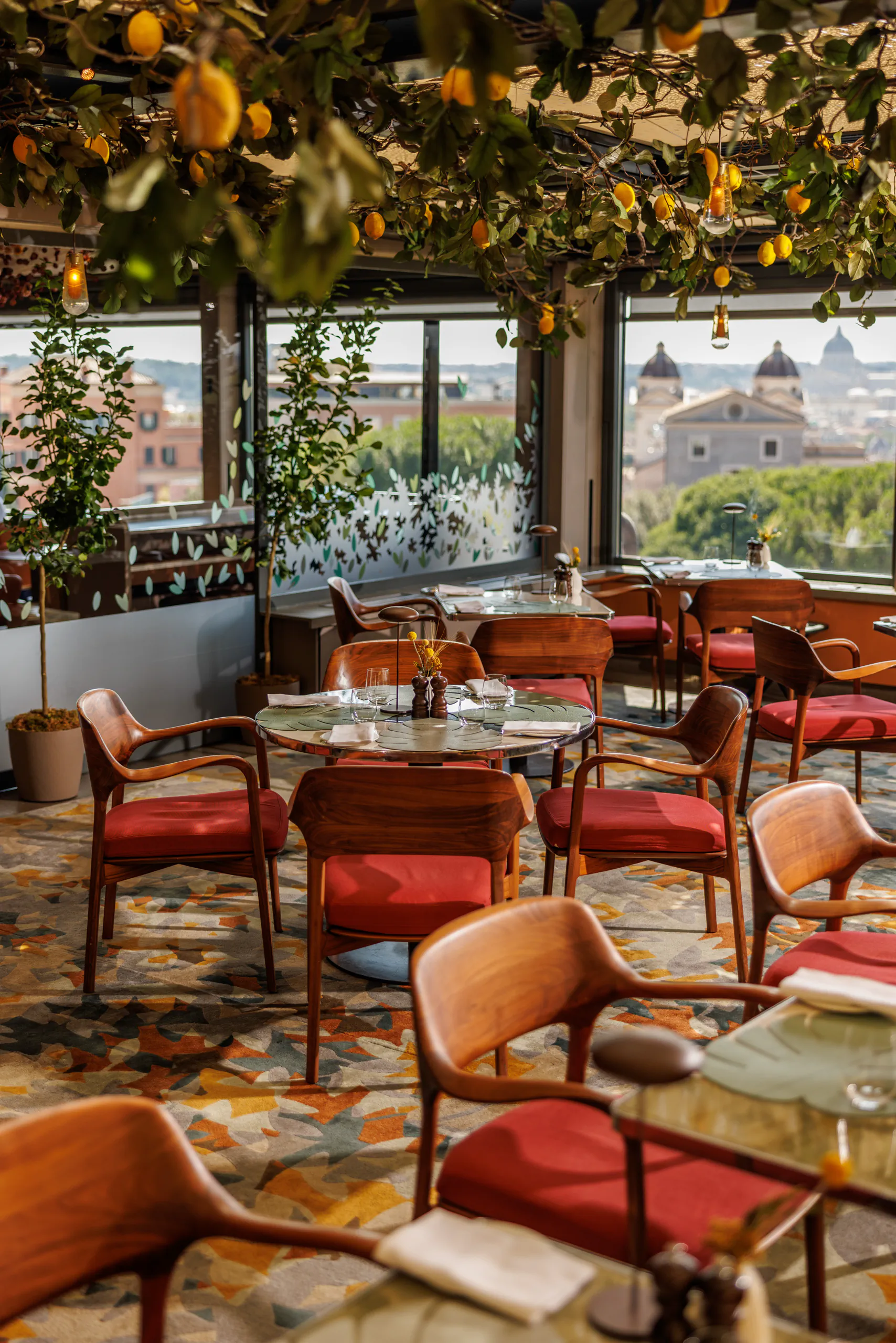 Rooftop restaurant with red chairs and greenery overlooking Rome — Hotel Eden, Rome