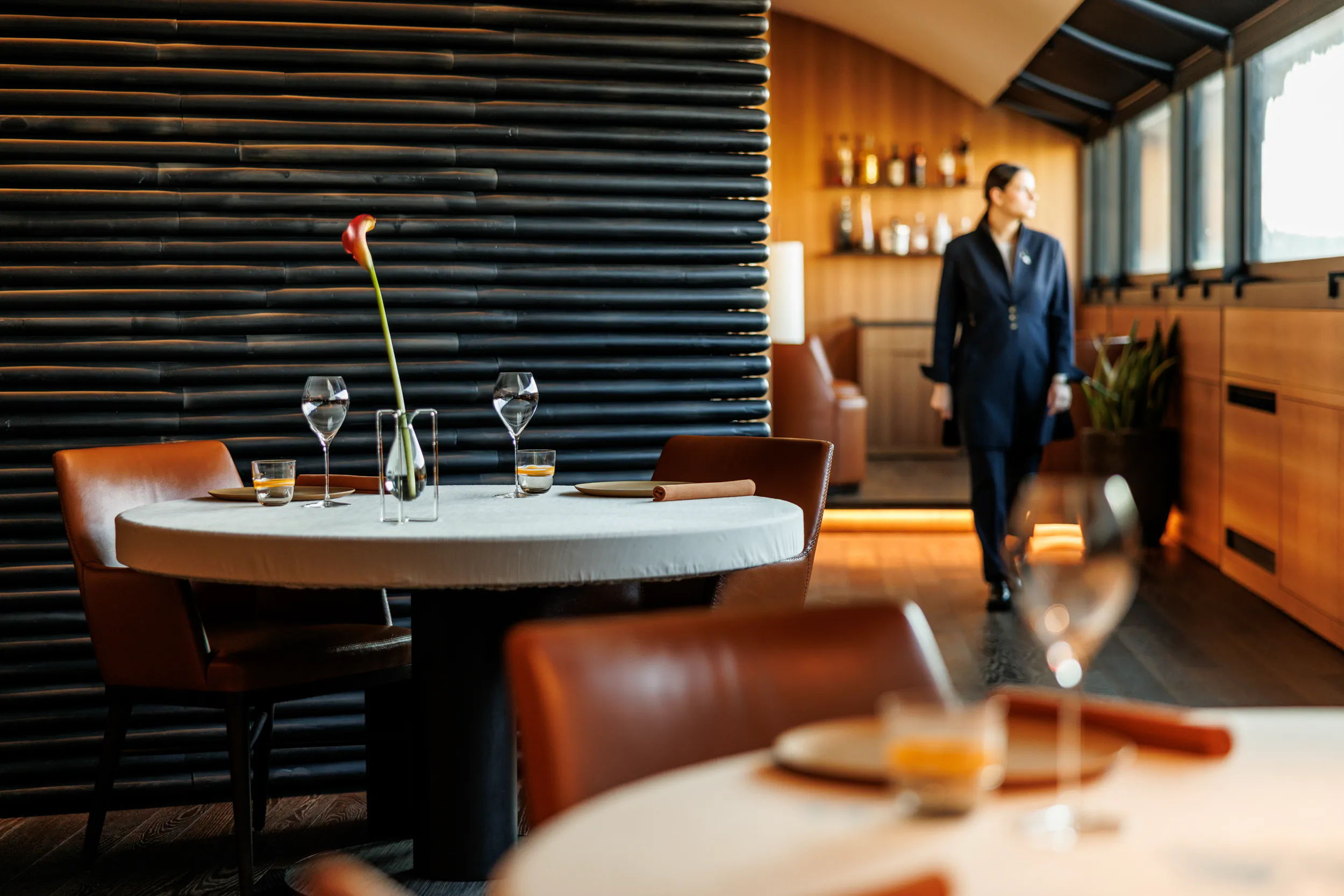 Elegant modern restaurant with dark wood walls and a man walking — Ristorante Andrea Aprea, Milan